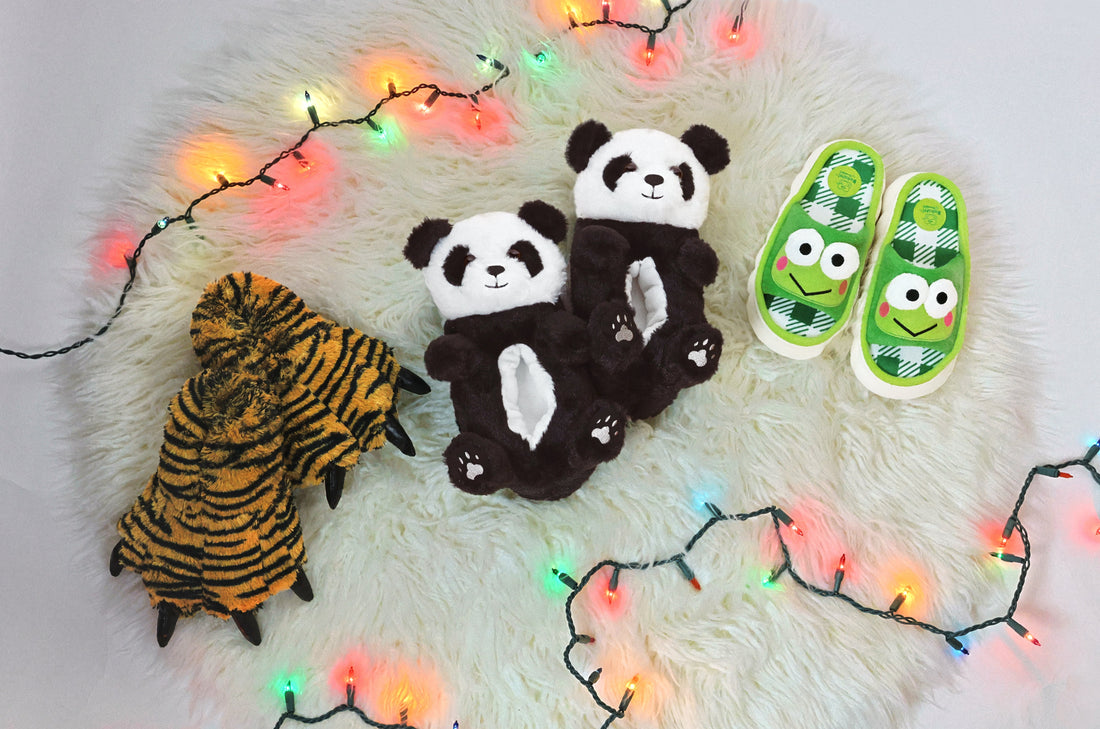 Three pair of kids slippers on a white carpet with holiday lights around them
