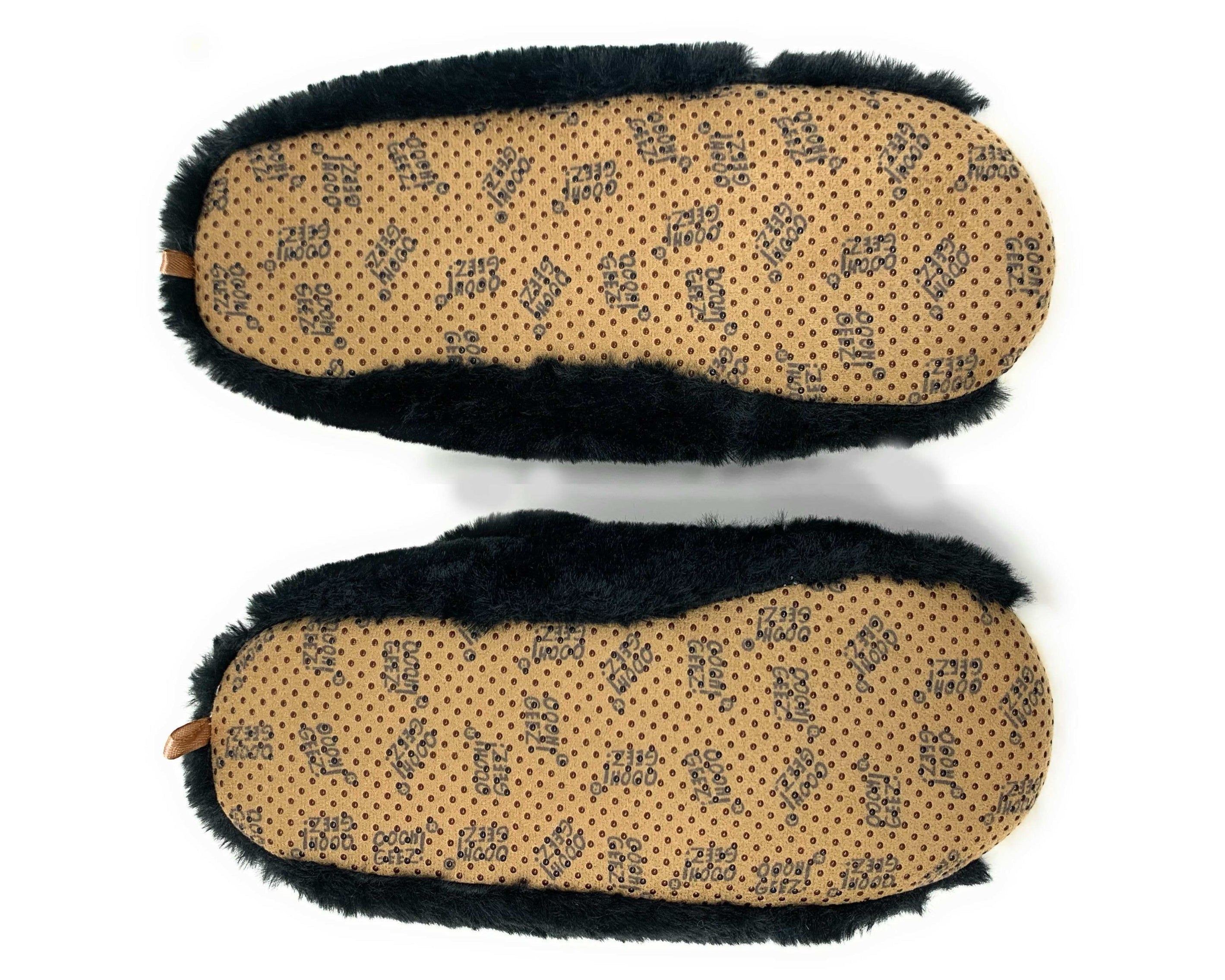 A pair of slippers shown from the bottom, featuring a tan footbed with a repeating black brand name pattern and black faux-fur trim along the sides.