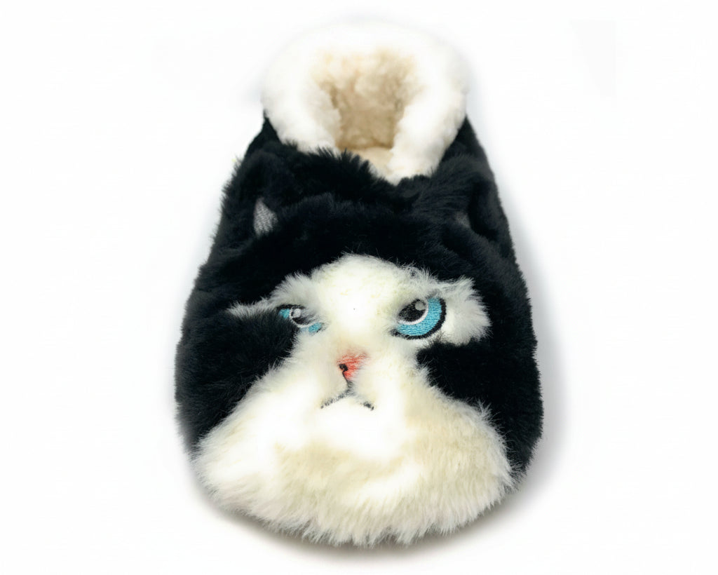 A novelty plush slipper shaped like a cat's face, featuring black and white faux fur with embroidered blue eyes and a small pink nose, shown on a plain white background.