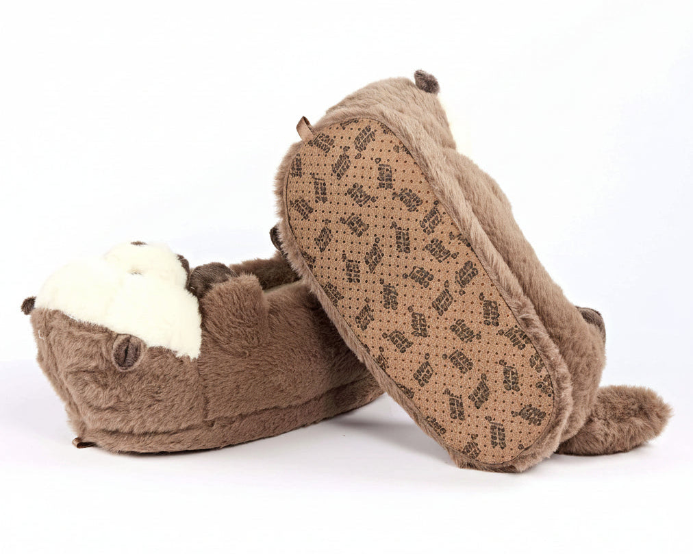 A pair of plush brown slippers shaped like otters, with one slipper showing the white faux-fur face and the other showing the patterned brown sole, set against a plain white background.