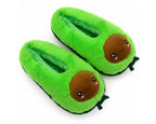 A pair of plush avocado-themed slippers in bright green with a cute cartoon face on the front and small green leaf details at the bottom, shown on a plain white background.