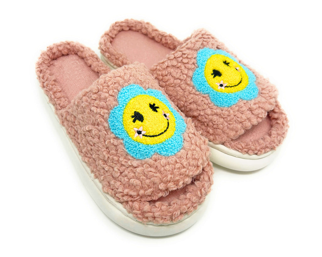 Pink slippers with smiley face designs on a white background