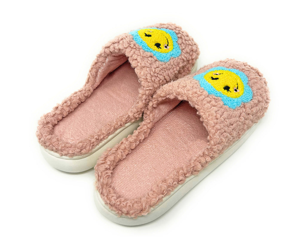 Pink slippers with cartoon smily face design on a white background