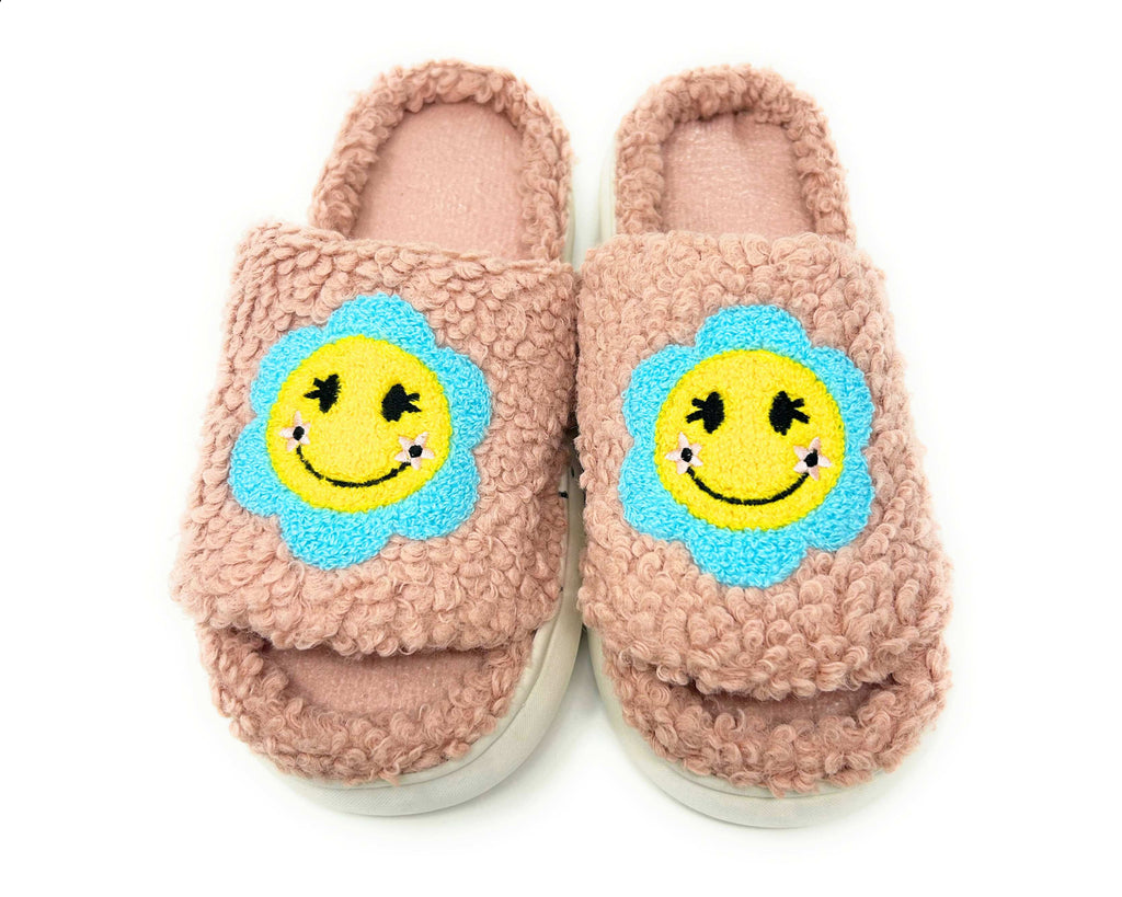Pair of pink slippers with smiley face design on a white background
