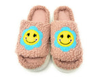 Pair of pink slippers with smiley face design on a white background