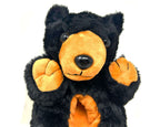 Black and orange plush bear slipper on a white background