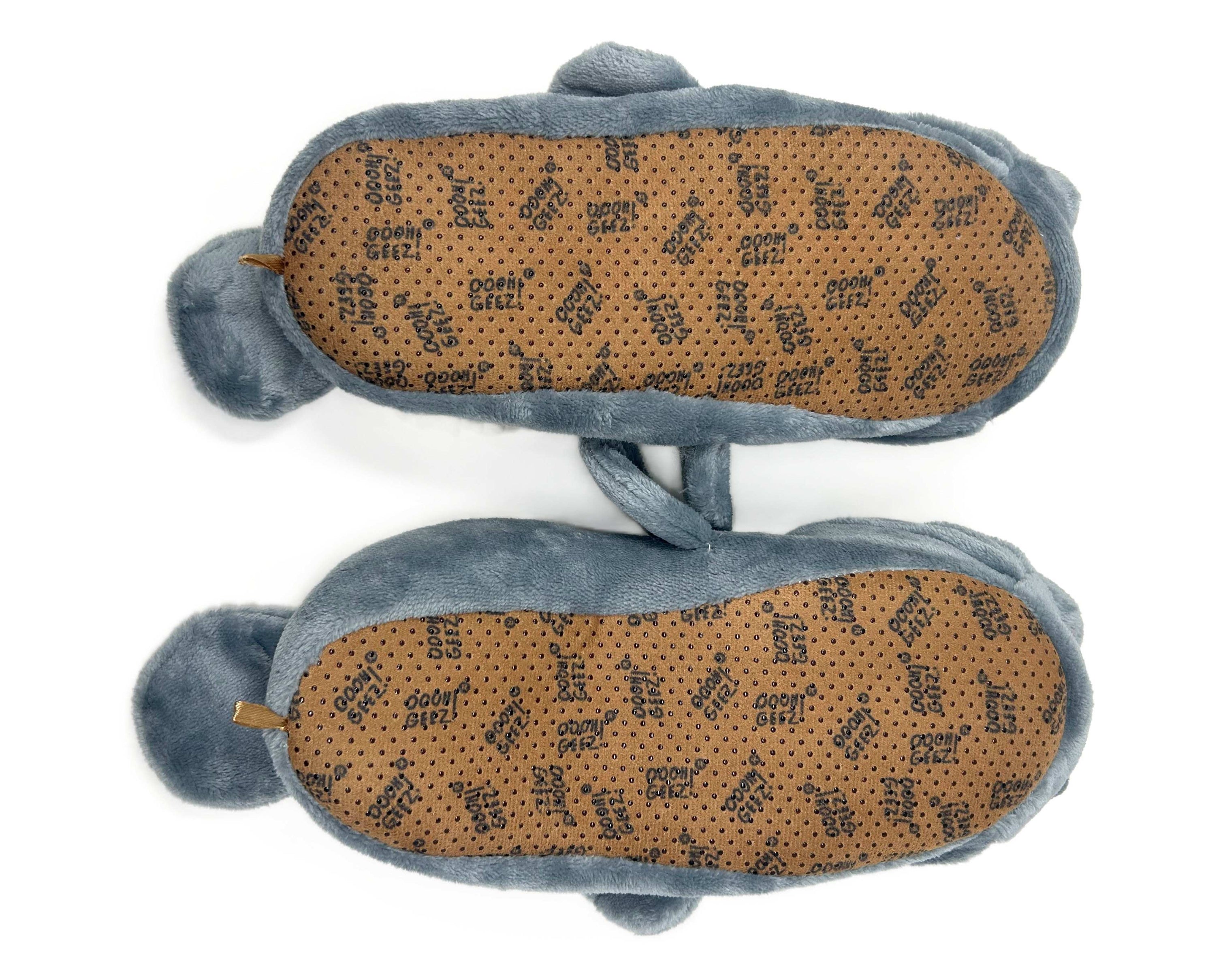 Bottom view of a pair of manatee slippers, showing faux suede footbeds with non-slip grips on a white background