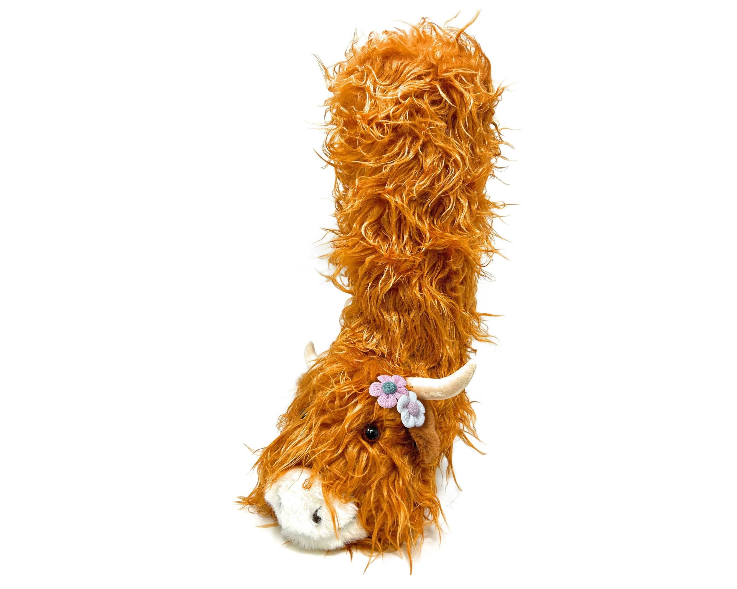 Fuzzy plush highland cattle slipper sock with orange faux fur and a floral headband on a white background