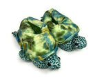 Turtle-shaped slippers with green and blue pattern on a white background