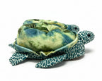 Plush turtle slippers with green and blue pattern on a white background