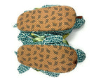 Two plush turtle slippers turned upside-down to show non-slip on a white background