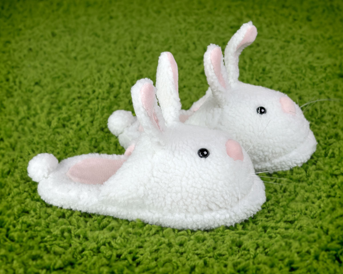 Pair of white bunny slippers on a green textured surface