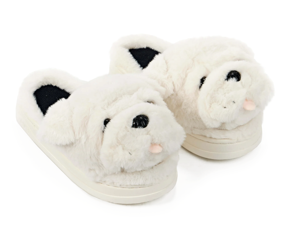 A pair of plush white slippers shaped like a dog or bulldog face, with black plastic eyes and nose and a small pink tongue, shown on a clean white background.