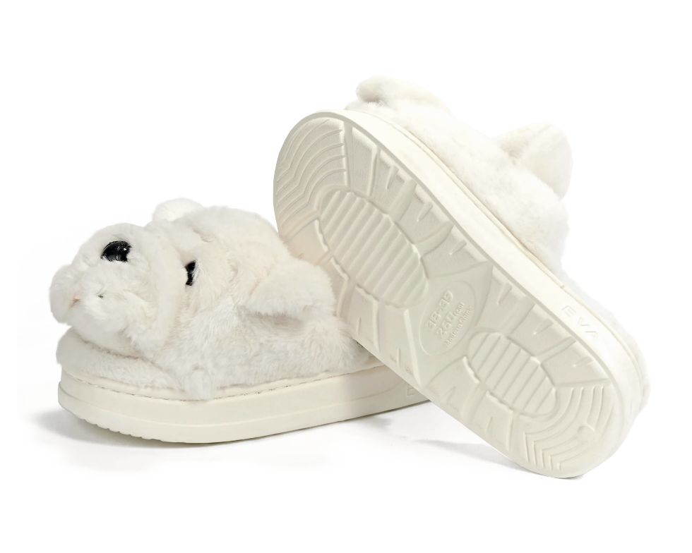 A pair of plush white slippers shaped like bulldogs, shown on a clean white background with one slipper standing upright to display the sole.