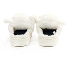 A pair of fluffy white slippers with long faux-fur trim and thick white soles, shown from the back on a white background.