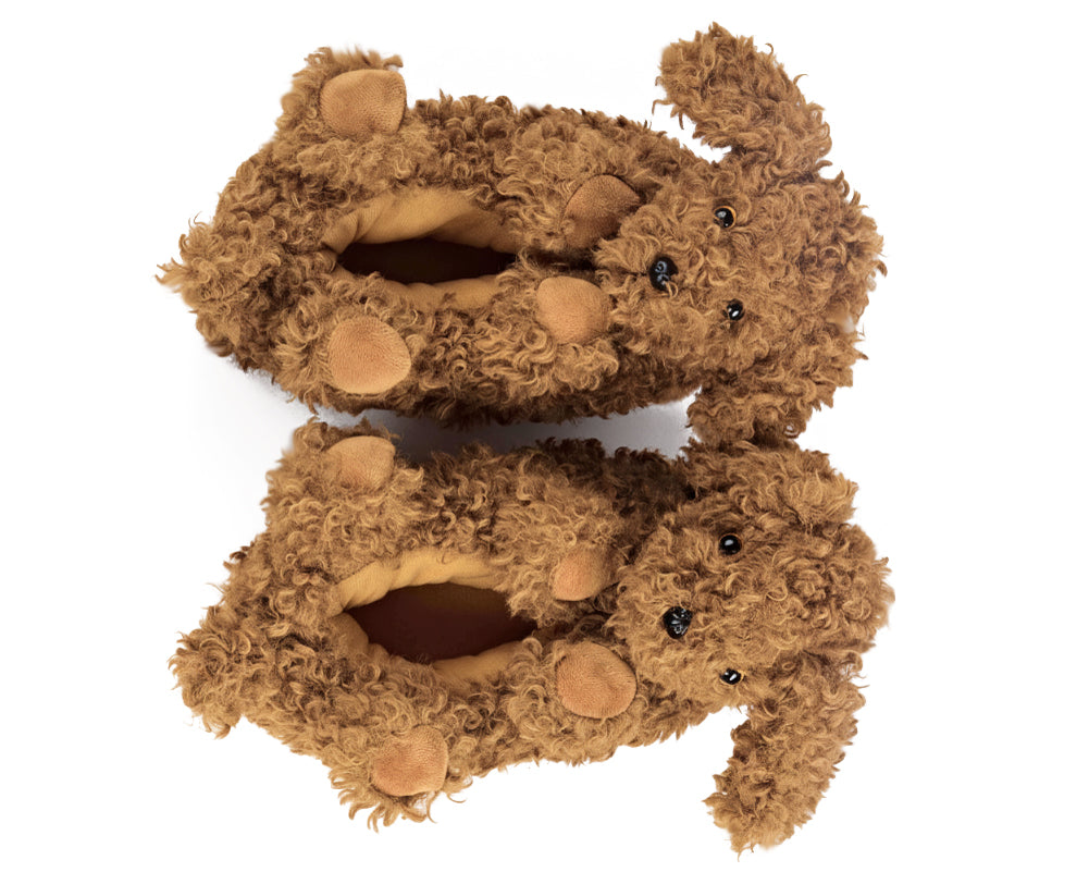 Pair of doodle dog slippers seen from above, showing curly brown plush, ears, paws, tails and black eyes and noses, on a white background