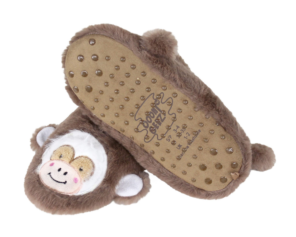 A pair of plush monkey-themed slippers shown on a white background, with one slipper upright to display the monkey face and the other lying on its side to show the tan non-slip sole with rubber studs.