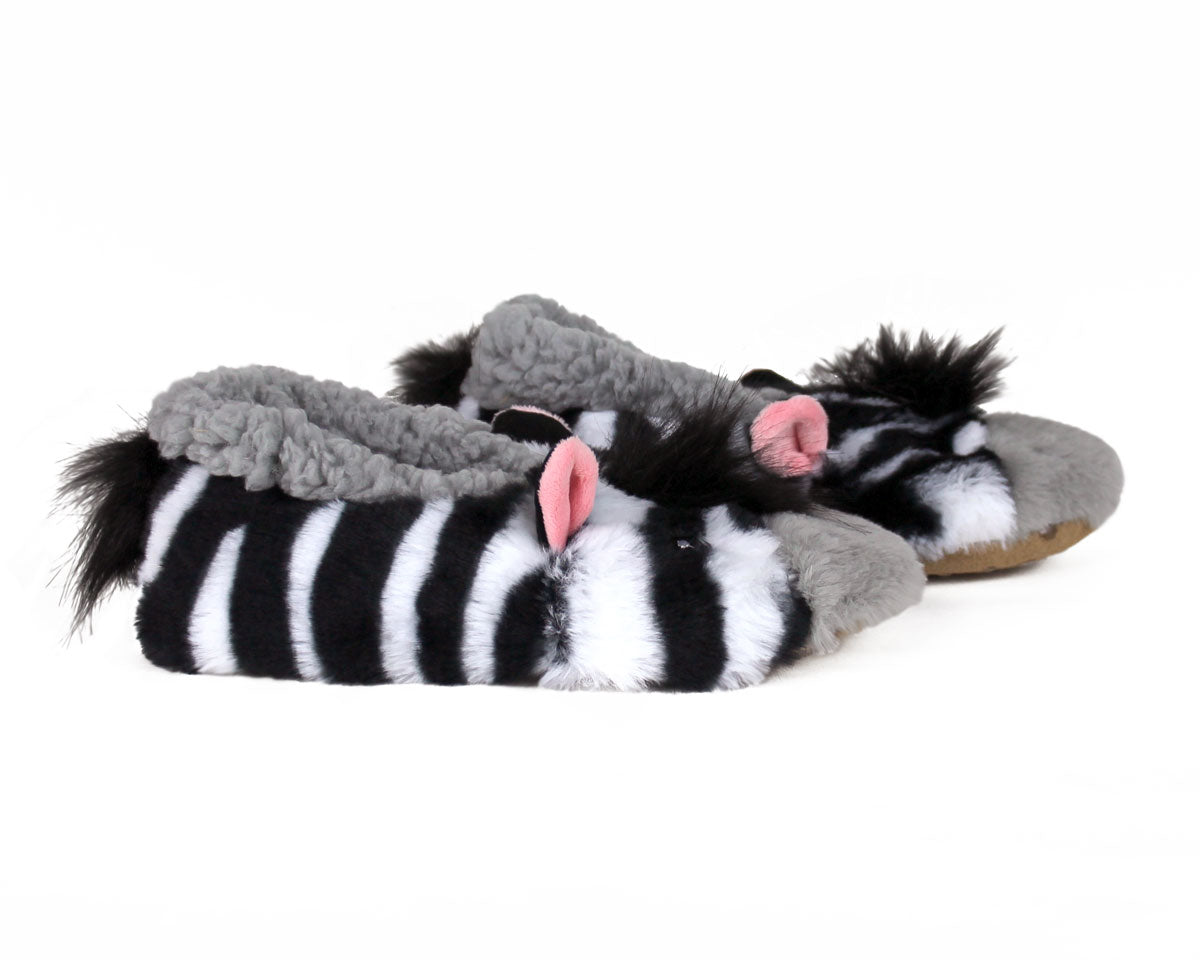 Zebra-patterned plush slippers with gray fuzzy trim, black and white stripes, and pink ears, shown on a plain white background.