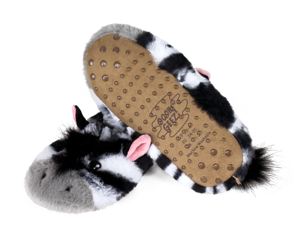 A pair of plush zebra slipper shoes with black and white fur-like bodies, pink ears, and a brown sole with non-slip grips, shown on a white background.