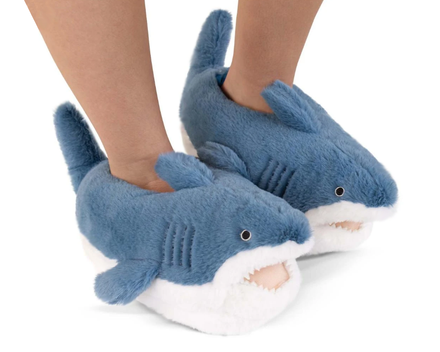 Legs wearing a pair of fuzzy shark slippers with blue and white, plush, felt teeth, gills fins and eyes.