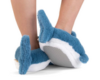 A pair of legs wearing plush shark slippers shown from the back, the slippers have tail fins. 