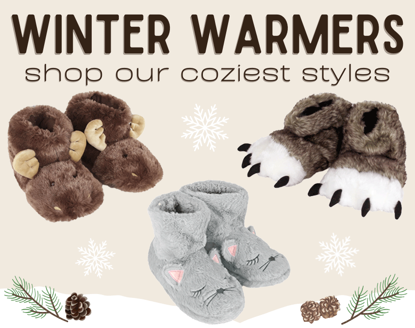 Pair of brown moose-shaped slippers and gray cat-shaped slippers with snowflake and pine branch decorations on a beige background. Text reads "Winter Warmers: shop our coziest styles"